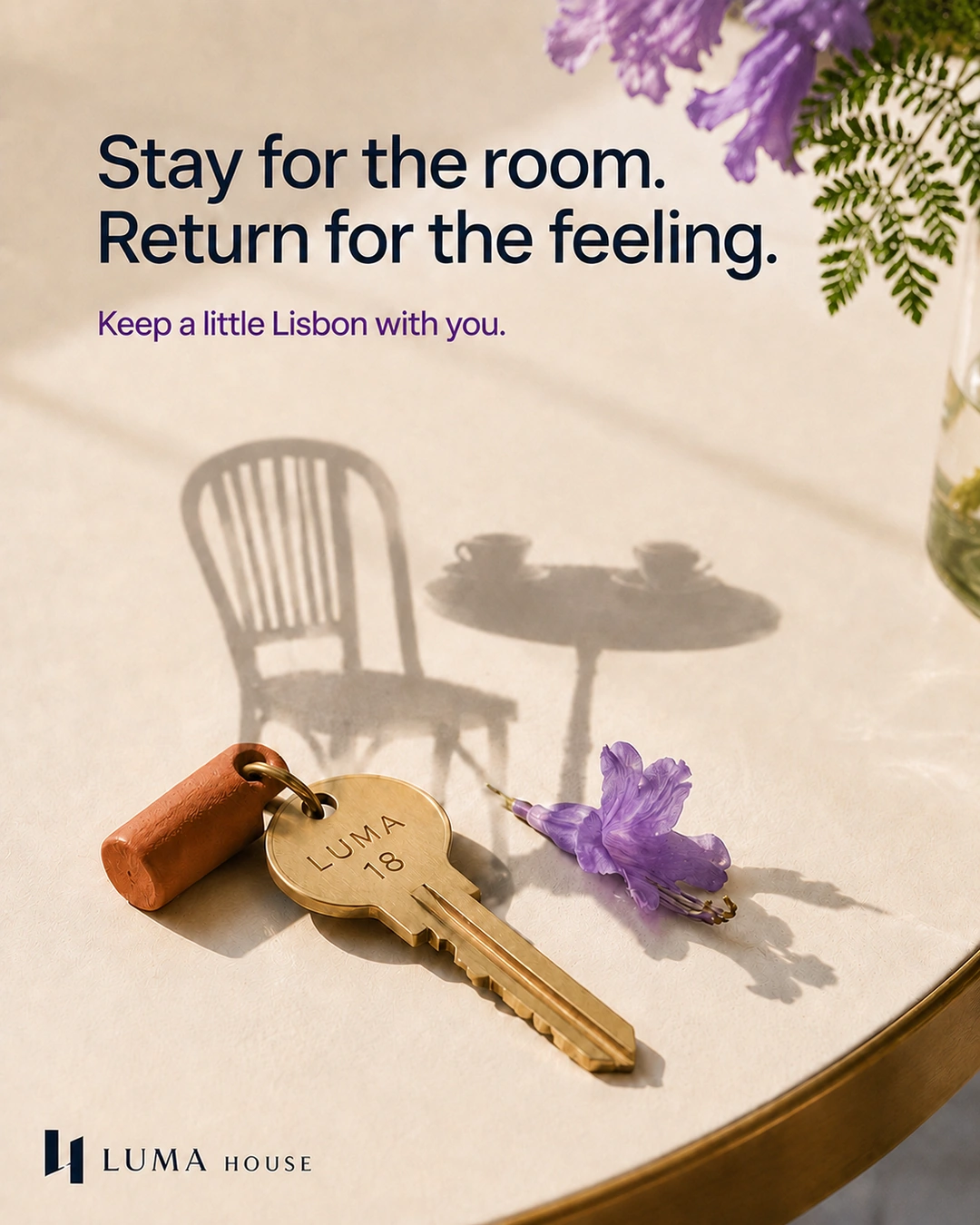A brass room key and purple flower cast the imagined shadow of a café chair and table.